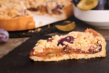 Piece of crumble plum tart, homemade plum pie, delicious cake on plate
