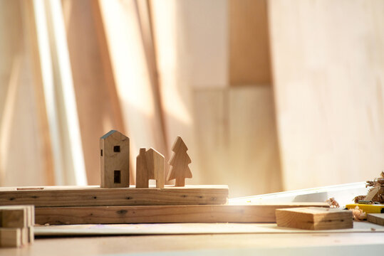 Wooden little houses and Christmas tree in workshop studio, DIY wood work, wooden plank in background, concept of DIY