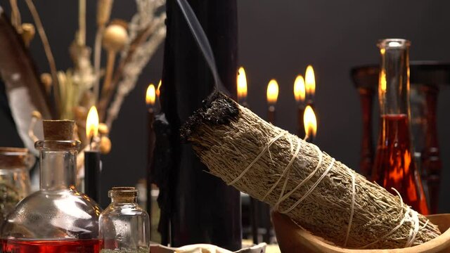 Smudging and spiritual burning of smoking sage or smudge stick concept. Close up macro of weeds for energy clearing and healing. Magic chemistry and witch craft.