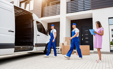 Two removal company workers unloading boxes from minibus into customer's home