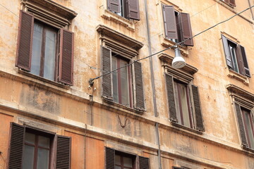 Fototapeta na wymiar Rome Via del Corso Street Close Up with Typical Brown House Facades with Shutters and Hanging Street Light, Italy