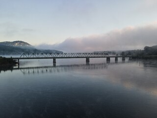 Fototapeta na wymiar A bridge over water with a foggy sunrise. Bridge is on Lake Allatoona in Cartersville