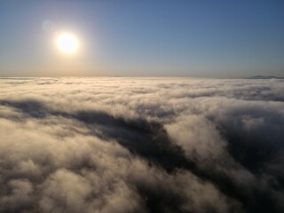 Dense fog clouds with the morning sunrise. Clouds formed over a lake approximately 100 feet below the clouds. Image could be drone an airplane window or drone.
