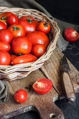 Fresh red tomatoes in whicker basket on black background.