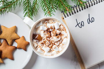 Christmas background. To-do list and festive cocoa with marshmallow on white marble. New Years...
