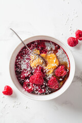 Chia pudding in bowl with raspberries, peanut butter and coconut. Vegan food concept.