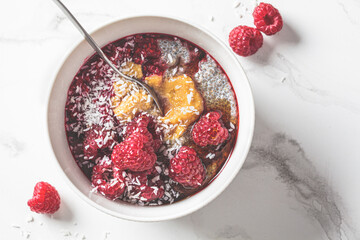 Chia pudding in bowl with raspberries, peanut butter and coconut. Vegan food concept.