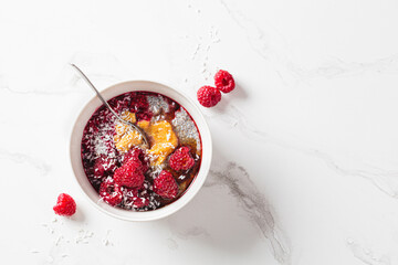 Chia pudding in bowl with raspberries, peanut butter and coconut. Vegan food concept.