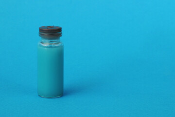One glass clear bottle with a red vaccine medicine on a blue background.