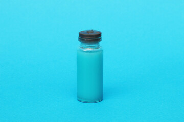 One glass clear bottle with a red vaccine medicine on a blue background.