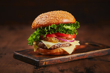 Homemade burger with beef, cheese and onion marmalade on a wooden board. Fast food concept, american food