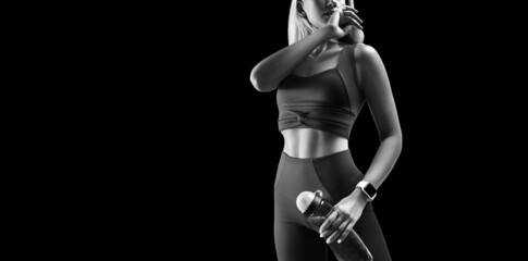 Fototapeta na wymiar Black and white portrait of fitness athletic female body in sports clothing showing her well trained body isolated on black. Copy freespace on left
