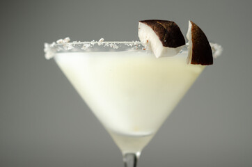 Coconut cocktail in martini glass based on the rum decorated with coconut flakes and coconut pieces