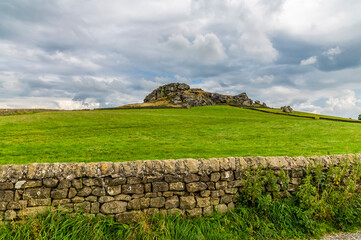 A view past a dry stone wall towards the Almscliffe crag in Yorkshire, UK in summertime