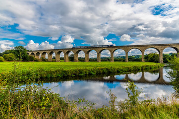 Fototapeta premium A view of a train crossing the Arthington Viaduct in Yorkshire, UK in summertime