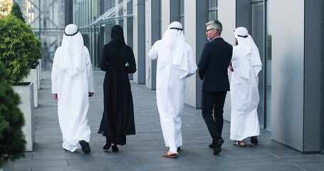 Full length view of the multi-ethnic group of business people are walking outdoors in city street...