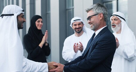 Good work. Close-up of view of strong handshake of intelligent businesspeople. Elegant diverse people are standing near the office. Business concept