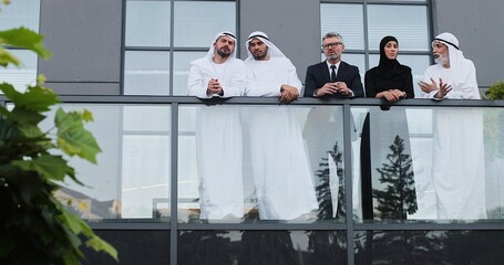 Wow. Full length view of the group of arabian business team standing at the balcony and gesturing...