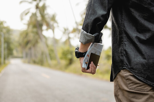Close up male traveler hands holding map and passport in forest