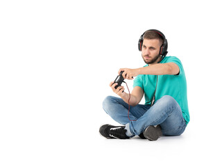 Young man playing videogames with a controler and a headphones in a white background