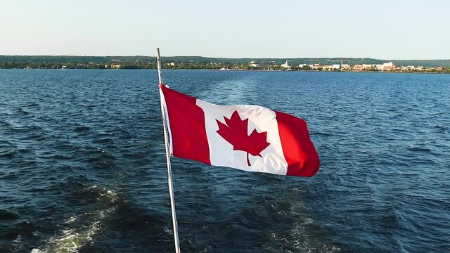 Canadian flag blowing in the wind during a ferry ride on a beautiful lake in Canada.