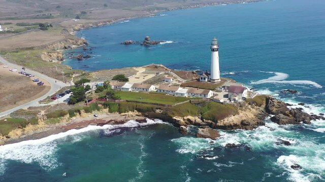 Pacific Ocean waves crash against the scenic coastline of California near Santa Cruz. A beautiful lighthouse stands on the edge of the sea providing visual warning for passing ships.