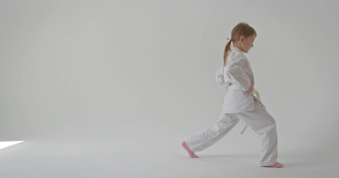 The girl performs lunges and keeps her hands on her belt. Video where a child performs sports exercises.