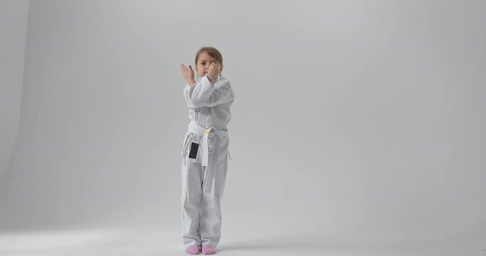 The child in full growth performs karate exercises. Serious look of a child engaged in karate.