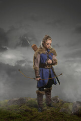 Beautiful female viking woman warrior in battle with ax and bow with arrows. Amazon fantasy blonde...