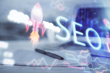Multi exposure of SEO drawings and desk with open notebook background. Concept of Search...