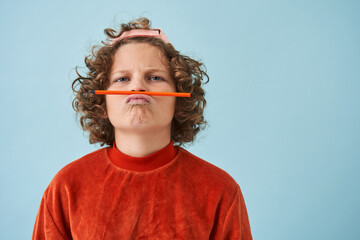 Little boy joking while holding pencil over mouth