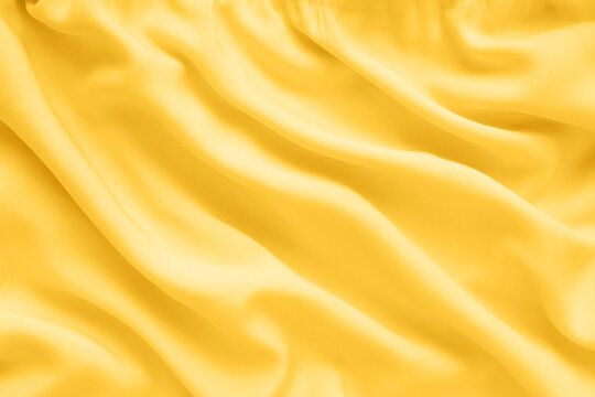 Yellow silk texture, abstract background luxury fabric with wavy folds