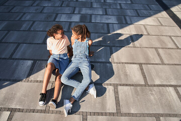 Girlfriends sitting on skateboard in city area