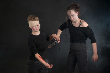 Couple of dressed up teenage kids during a machete mock fight in Halloween zombie costumes - obrazy, fototapety, plakaty