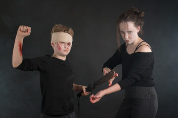 Couple of dressed up teenage kids during a machete mock fight in Halloween zombie costumes, demonstrating how to block a knife