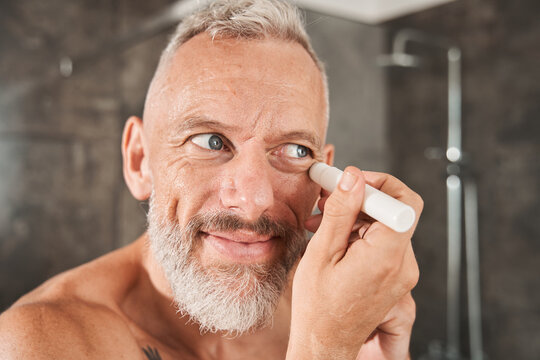 Mature Man Apply Under Eye Concealer On Face