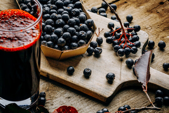 Fresh aronia berries and berry juice in a glass.