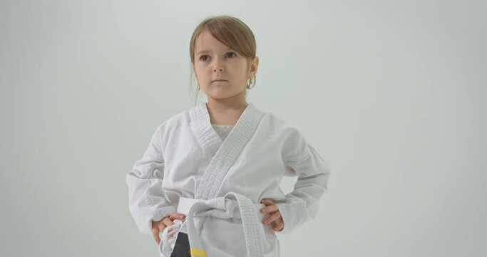 The girl is engaged in karate video lessons. Looks at the screen and repeats the exercises.