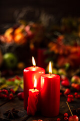 Red candles are lit on a wooden table. Candles surrounded by lights