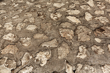 Old paved vintage alley, uneven paseo way footpath.Retro pathway castle of design farm town.Aged rough grunge dry stone blocks of lane. Damaged shabby rustic nice bumpy hard durable relief sett avenue