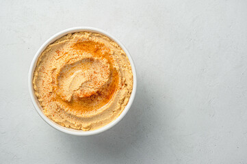 Traditional hummus flavored with olive oil and paprika on a gray background. Oriental, healthy food.