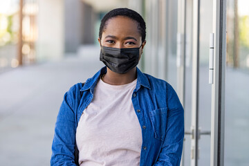 Masked african-american woman on a city street. Teenage girl patient, copy space. Epidemic, pandemic, corona virus protection, healthy lifestyle, people concept