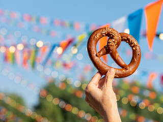 Pretzel in hand - traditional snack bread in Europe. Fast food and street food concept background   