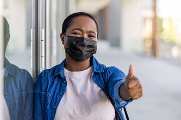 Masked african-american woman on a city street. Teenage girl patient, copy space. Epidemic, pandemic, corona virus protection, healthy lifestyle, people concept