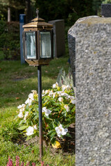 Closeup of metallic lanterns in front of tombstones in the cemetery.