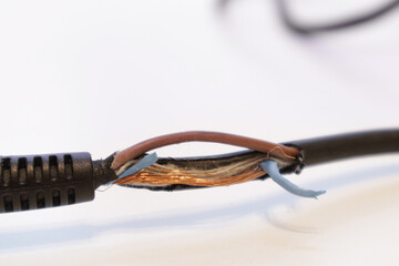 Broken power cord for home electrical appliances, electric tools. Damaged cable insulation. Close-up, soft focus