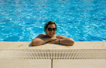 beautiful young woman in a sunglasses relaxing in the pool