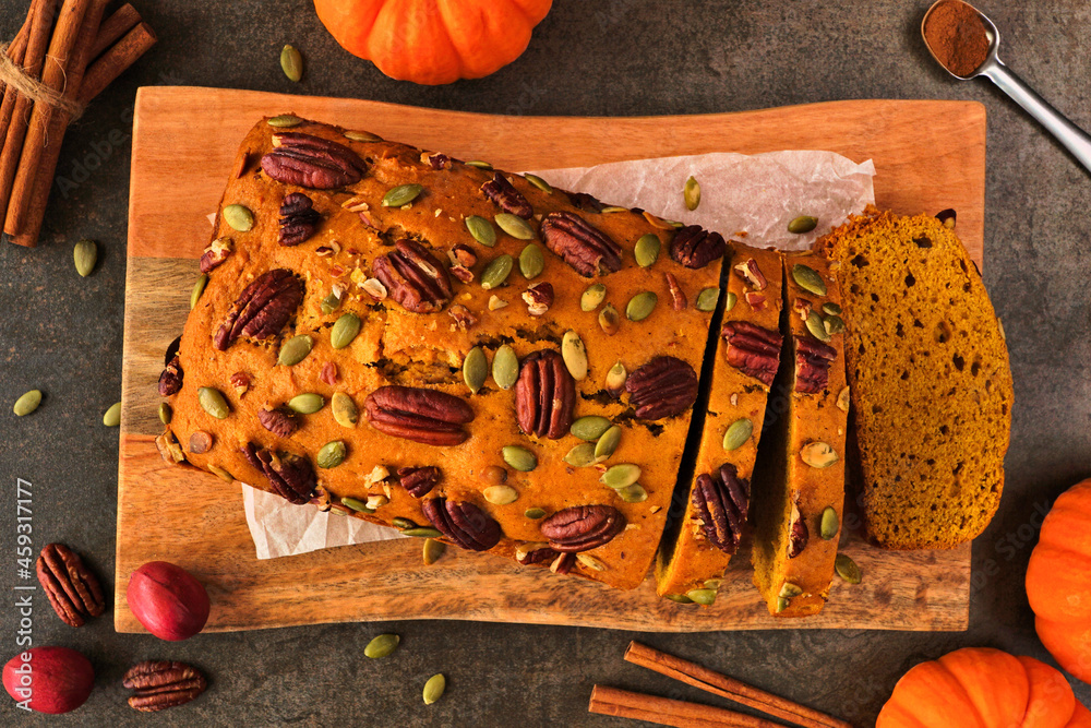 Poster autumn pumpkin bread sliced. above view table scene over a dark background.