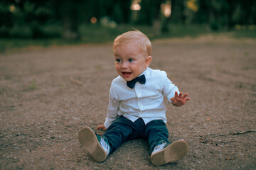 A portrait of a baby boy in a business suit walks on the pavement and shouts displeasedly.