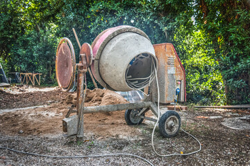 Concrete mixer, sand and gravel in a garden